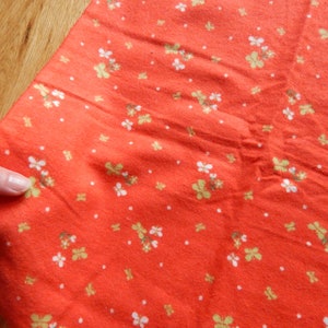 Puede incluir: Tela roja con un patr&oacute;n floral blanco y verde.