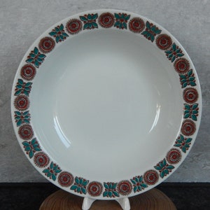 May include: White ceramic bowl with a decorative border of red, brown, and teal floral designs.