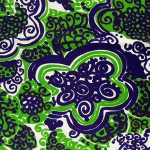 May include: A white fabric with a green and purple abstract pattern. The pattern features swirls, dots, and lines.