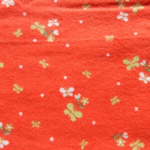 Puede incluir: Tela roja con un patr&oacute;n floral blanco y amarillo. La tela tiene una superficie texturizada.