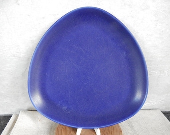 May include: A solid blue triangular ceramic plate. The plate has a smooth, slightly textured surface.