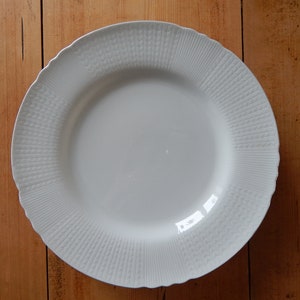 Puede incluir: Plato de cena de cerámica blanca con un patrón texturizado en relieve alrededor del borde.