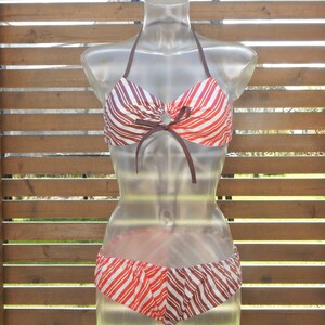 Può includere: Top e fondo bikini a righe rosse e marroni con un fiocco marrone al centro della parte superiore.