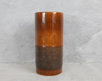 Könnte beinhalten: Eine braune Keramikvase mit einem strukturierten, gesprenkelten braunen Band um die Mitte.