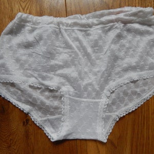 May include: White lace underwear with a delicate floral pattern. The underwear has a wide elastic waistband and a lace trim.