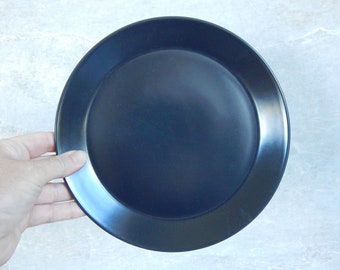 May include: A dark blue ceramic dinner plate with a slightly raised rim.