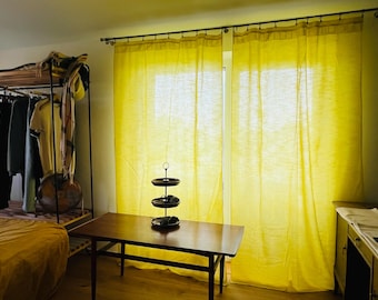 May include: A pair of bright yellow curtains hanging from a metal rod in front of a window. The curtains are made of a semi-sheer fabric that allows light to pass through, creating a vibrant glow in the room while covering the window area.