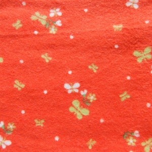 Puede incluir: Tela roja con un patr&oacute;n floral blanco y amarillo. La tela tiene una superficie texturizada.
