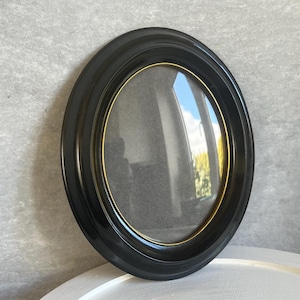 May include: A black oval picture frame with a gold inner edge. The frame is empty and ready for a photo.