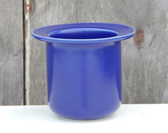 May include: A deep blue ceramic planter with a wide rim. The planter is made of a smooth, glossy material.