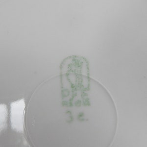 以下が含まれることがあります： 緑と白の磁器のマークで、花柄のデザインと数字の32が描かれています。