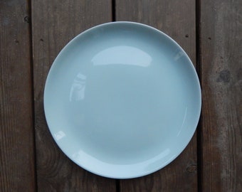 May include: A light blue ceramic dinner plate on a wooden surface.