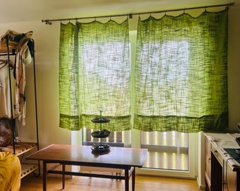 May include: A pair of lime green curtains with a textured, woven appearance hanging from a metal rod. The curtains feature a semi-sheer quality that allows light to pass through, displaying a horizontal slub pattern across the fabric surface.