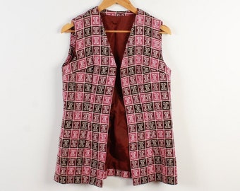 May include: A sleeveless vest with a geometric pattern in shades of pink, brown, and white. The vest has a V-neck and a long, flowing style.