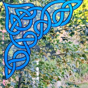 Könnte beinhalten: Ein eckförmiges Dekorationsobjekt mit einem leuchtend blauen keltischen Knotenmuster und schwarzen Umrandungen. Das Design besteht aus ineinandergreifenden Schleifen und Linien, die eine durchgehende, komplexe geometrische Form mit einer spitzen Ecke bilden.