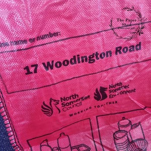 May include: A pink plastic bag with black text that reads "17 Woodington Road". The bag also features the North Somerset Council logo and the text "Working Together".