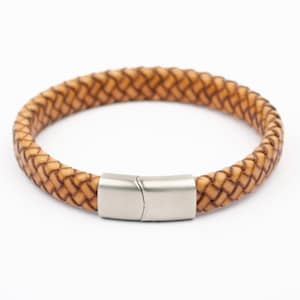 Puede incluir: Pulsera de cuero trenzado marrón claro, con cierre de acero inoxidable. El diseño trenzado de la pulsera es visible. Se presenta sobre un fondo blanco. Un accesorio elegante para el uso diario.