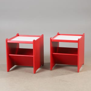 Peut inclure: Deux tables d'appoint rouges en bois avec des plateaux blancs. Chaque table a une étagère inférieure et une forme rectangulaire. Les tables sont en bois et ont un design simple et moderne. Les tables conviennent à un salon ou une chambre.