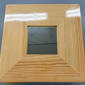 May include: A natural wood picture frame with a clear glass insert. The frame has a simple, rectangular design and a light wood finish.