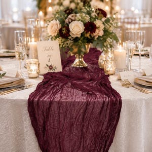 May include: A beautifully set table with a white tablecloth, gold-edged plates, and crystal glasses. A deep burgundy runner is paired with a floral centrepiece. Table number 7 is visible.