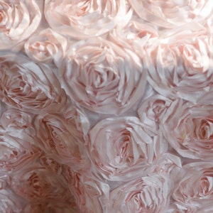 Puede incluir: Primer plano de un mantel de tela rosa claro con un diseño texturizado de rosetas.