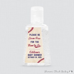 May include: Clear hand sanitizer bottle with a white cap. The label reads "PLEASE BE Germ-Free FOR THE Mom-to-Be" and "Addison's BABY SHOWER OCTOBER 20, 2025". Baseball stitching design accents the label.