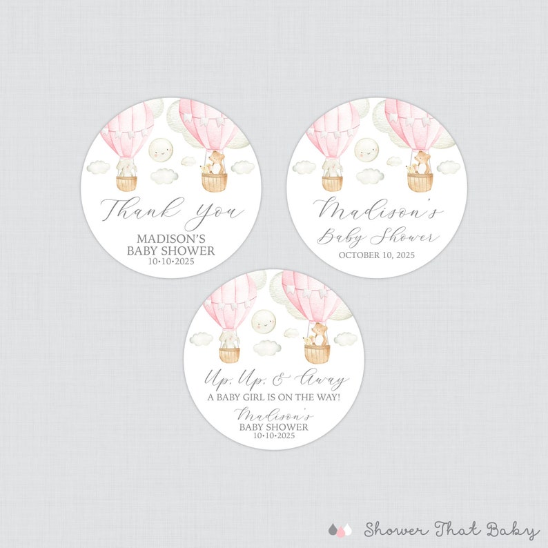 May include: Three round pink and white baby shower favor stickers with a hot air balloon theme. The stickers feature a pink hot air balloon with a fox and a bear in a basket. The text on the stickers reads "Thank you Madison's Baby Shower 10-10-2025", "Madison's Baby Shower October 10, 2025", and "Up, Up & Away A baby girl is on the way! Madison's Baby Shower 10-10-2025".