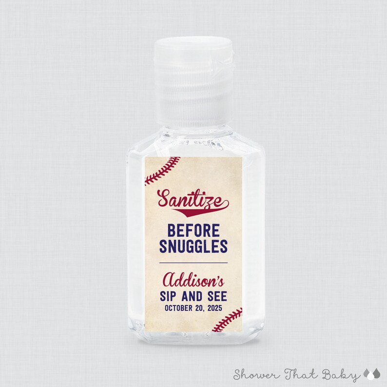 May include: Clear plastic hand sanitizer bottle with a white cap. The label reads "Sanitize BEFORE SNUGGLES" in red and blue, with "Addison's SIP AND SEE OCTOBER 20, 2025" below. Baseball stitching accents the design.