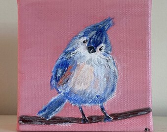 May include: A painting of a blue bird perched on a branch against a pink background. The bird has a white chest and a blue head. The painting is signed "BK" in the bottom right corner.