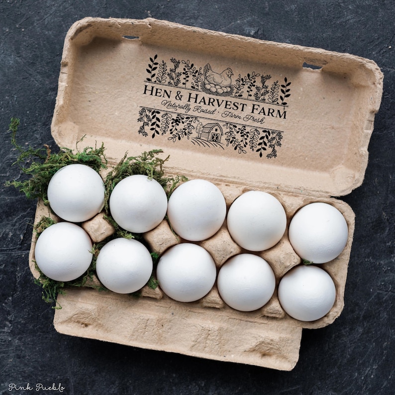 Custom rubber stamp impression reading "Hen & Harvest Farm – Naturally Raised · Farm Fresh" stamped in black ink on the inside lid of a green egg carton, shown with a dozen fresh brown eggs. Perfect for backyard chicken keepers, small farms, and handmade packaging.