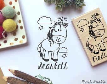 May include: A black and white illustration of a unicorn with a horn, mane, and tail. The unicorn is surrounded by clouds and stars. The name "Scarlett" is written below the unicorn. The image is on a white background.