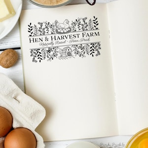 Custom rubber stamp impression reading "Hen & Harvest Farm – Naturally Raised · Farm Fresh" stamped in black ink on the inside lid of a green egg carton, shown with a dozen fresh brown eggs. Perfect for backyard chicken keepers, small farms, and handmade packaging.