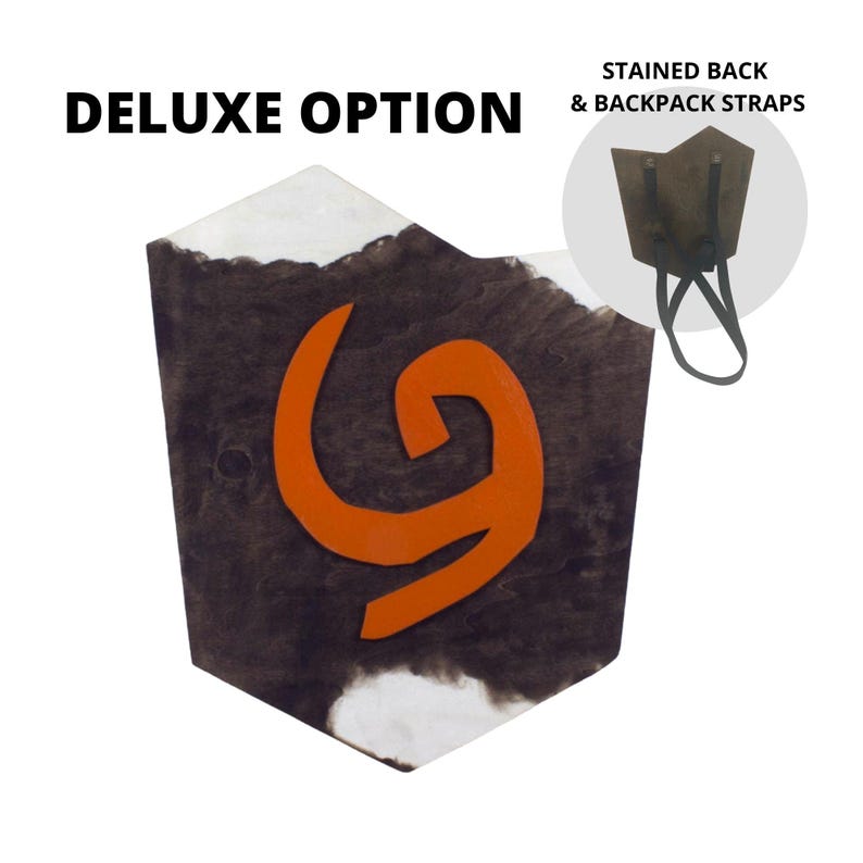 Puede incluir: Un escudo de madera con fondo marr&oacute;n oscuro y dise&ntilde;o de espiral naranja. El escudo tiene un borde blanco y el texto "DELUXE OPTION" en la parte superior. Una imagen m&aacute;s peque&ntilde;a muestra la parte trasera te&ntilde;ida y las correas.