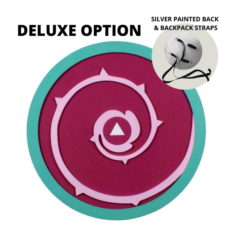 May include: A round, decorative shield with a teal border, a magenta center, and a light pink spiral design. The text "DELUXE OPTION" is at the top left. A smaller image shows the silver painted back and backpack straps.