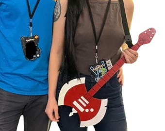 May include: A red and white axe-shaped guitar with a black strap. The guitar has a black and white sticker on the body.