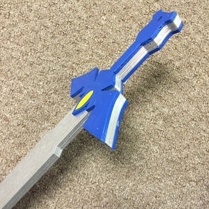 May include: A blue and silver plastic sword with a yellow detail. The sword is made of foam and is a prop.
