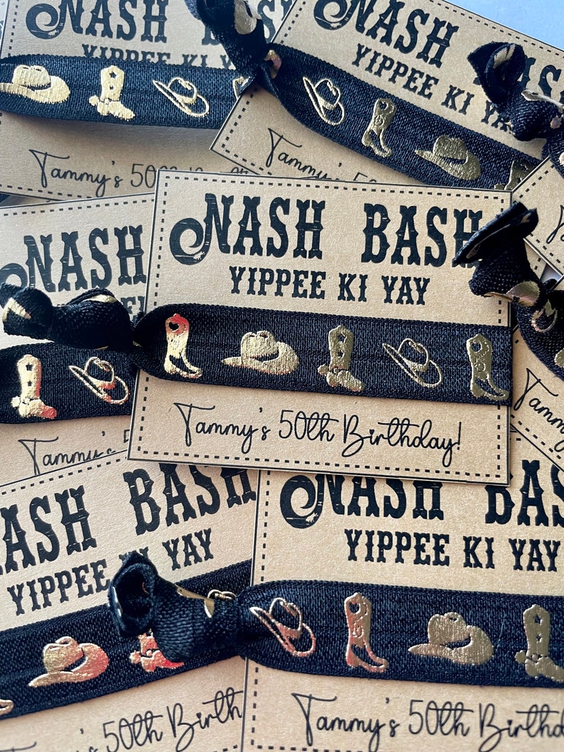 May include: Black and gold party favor bracelets with the text "Nash Bash Yippie Ki Yay" and "Tammy's 50th Birthday!" printed on a brown background.