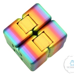 May include: A rainbow-colored infinity cube toy. The cube is made of multiple connected blocks that can be flipped and folded. The colors transition from green to purple, with gold-colored center pieces. The toy is designed for fidgeting and stress relief.