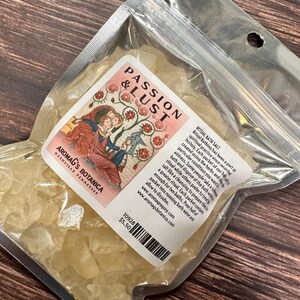 May include: A clear plastic bag filled with pale yellow bath salts. The label reads "PASSION & LUST" with an illustration of figures. Text on the label also includes "AROMAG'S BOTANICA NASHVILLE TENNESSEE" and details about the product.