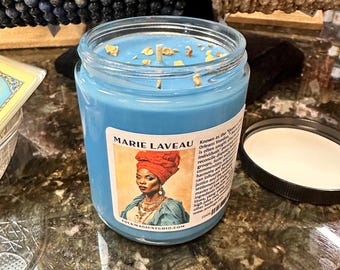 Puede incluir: Un tarro de vela de vidrio azul con una etiqueta blanca que presenta un retrato de Marie Laveau, una figura prominente en el vudú de Nueva Orleans. La etiqueta dice "Conocida como la "Reina del Vudú" de Nueva Orleans. A menudo se la busca para reconciliar disputas, fomentar la armonía y traer justicia y equilibrio a grupos, familias e individuos. Su influencia puede afectar la resolución de asuntos legales y puede traer justicia y equilibrio a otras áreas de la vida, incluyendo el amor, el dinero, la salud y las relaciones." La etiqueta también incluye el sitio web "folkmagicstudio.com".