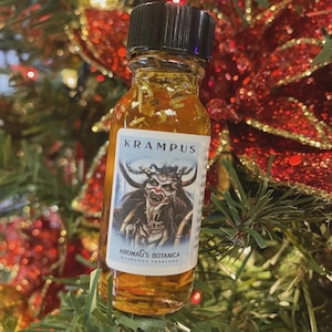 May include: A small glass bottle with a black cap, filled with a golden liquid and herbs. The label reads "KRAMPUS" and features an illustration of a horned demon. The bottle is from Aromag's Botanica, Nashville, Tennessee.