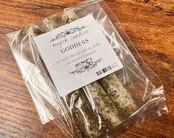 Puede incluir: Tres velas blancas con hierbas verdes y una etiqueta que dice "magick candles GODDESS dressed & blessed with oils, herbs, and mystical intention AROMAG'S 12700 5,99 €"