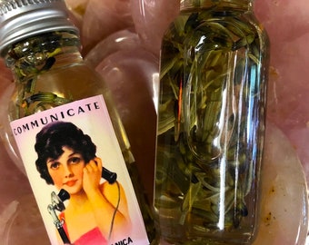 Könnte beinhalten: Zwei Glasflaschen gefüllt mit Flüssigkeit und Pflanzen. Eine Flasche hat ein Etikett mit dem Wort "COMMUNICATE" und einer Illustration einer Frau, die ein Vintage-Telefon benutzt. Das Etikett lautet auch "AROMAG'S BOTANICA, Nashville Tennessee."