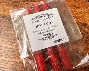 Puede incluir: Tres velas rojas en una bolsa de plástico transparente con una etiqueta blanca que dice "magick candles HOT FOOT dressed & blessed with oils, herbs, and mystical intention AROMAG'S BOTANICALS 12697 5,99 €"
