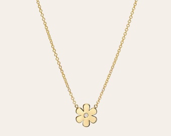 May include: A delicate gold chain necklace with a small, gold flower pendant featuring a single diamond in the center.