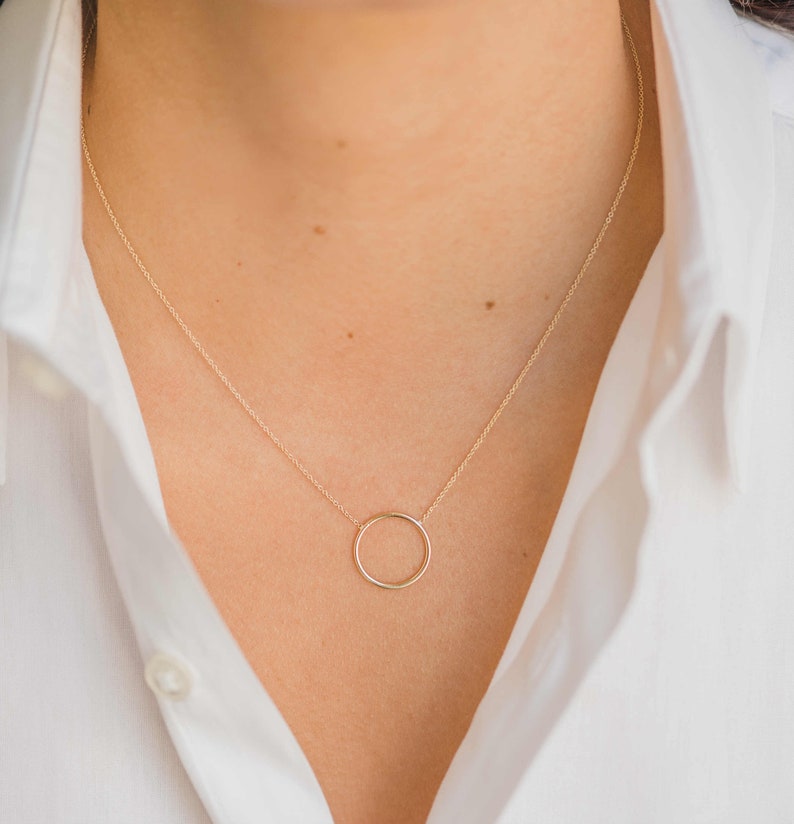 May include: A gold chain necklace with a simple circle pendant.