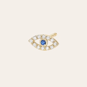 May include: A gold evil eye earring with a blue sapphire center and a halo of white diamonds.