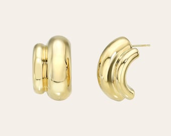 May include: A pair of gold hoop earrings with a unique, curved design. The earrings are made of a smooth, shiny metal.