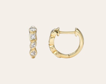 May include: A pair of gold hoop earrings with a row of small diamonds set in the front. The diamonds are in a variety of shapes, including round, square, and pear.