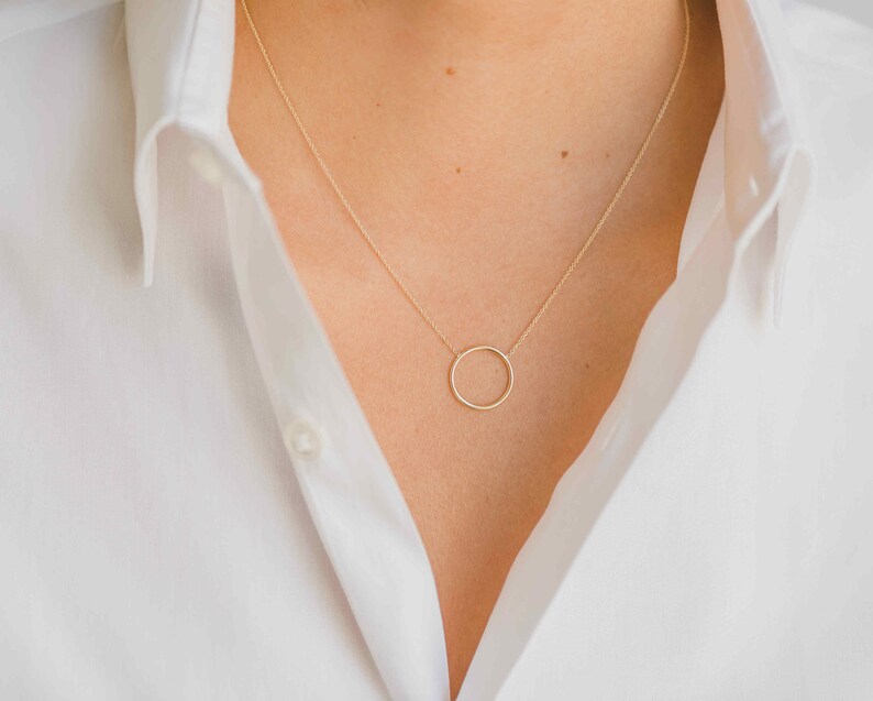 May include: A simple gold necklace with a delicate circle pendant.